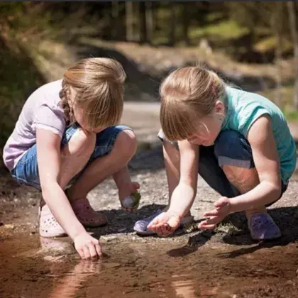 Man sieht Kinder, die in einer Pfütze spielen.