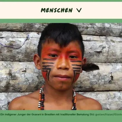 Man sieht einen indigenen Jungen mit traditioneller Gesichtsbemalung.