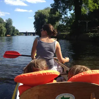 Eine Frau mit zwei Kindern paddelt durch einen Fluss.